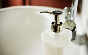 Soap dispenser next to a sink in a clean, white bathroom